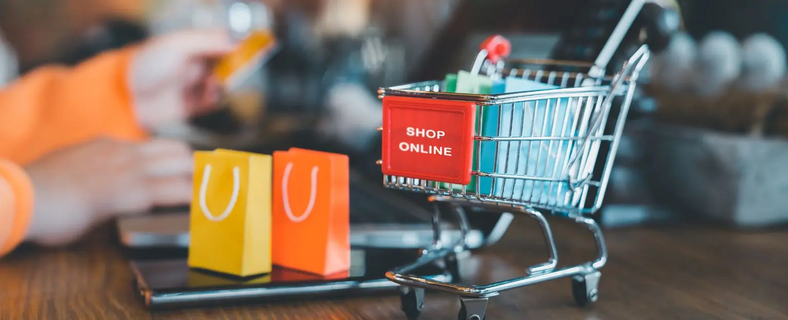 shopping cart and bags in front of a laptop for shop onlin