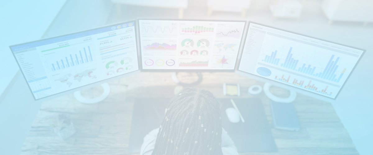 person sitting at a desk in front of 3 monitors with graphs for dashboards